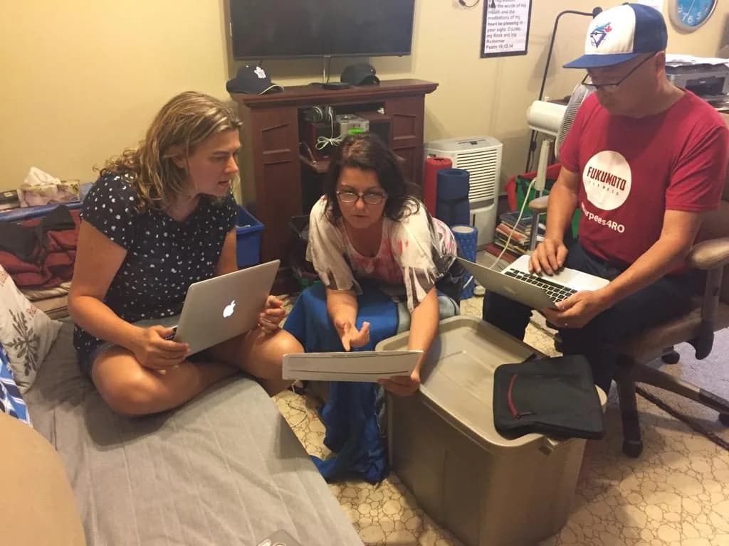 Three volunteers planning together with laptops and notebooks
