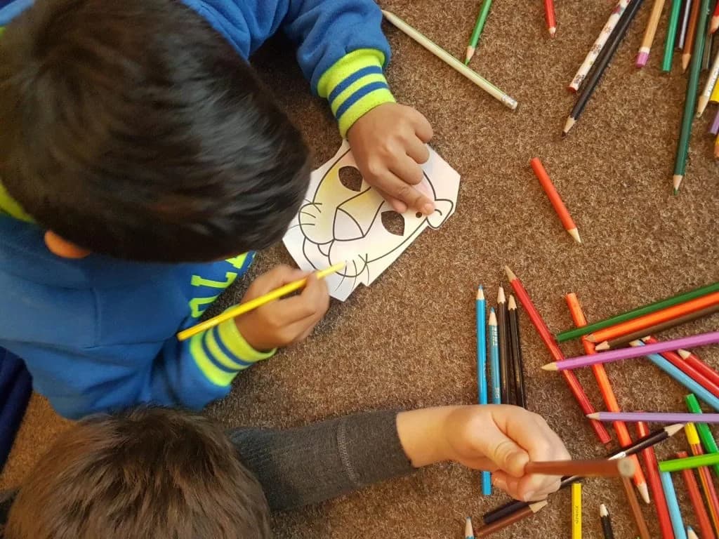 Copii colorează desene cu creioane la o masă de lucru